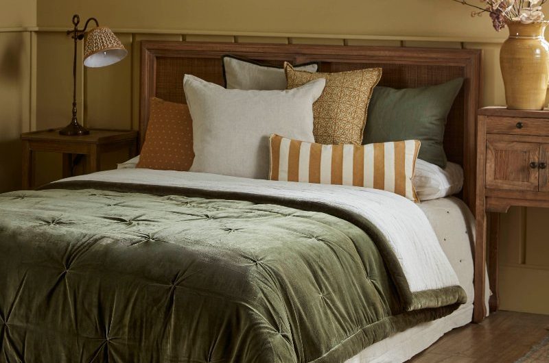 A rustic bedroom look with mustard yellow wall paint, rugs, and wooden furniture.