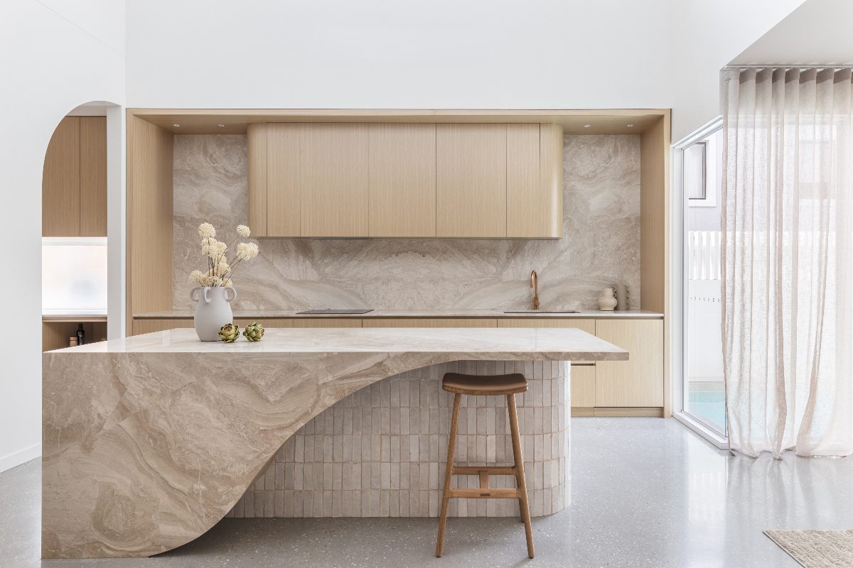 An Australian kitchen with s statement island with curved shapes and tactile tiles, topped with sandy-toned marble.