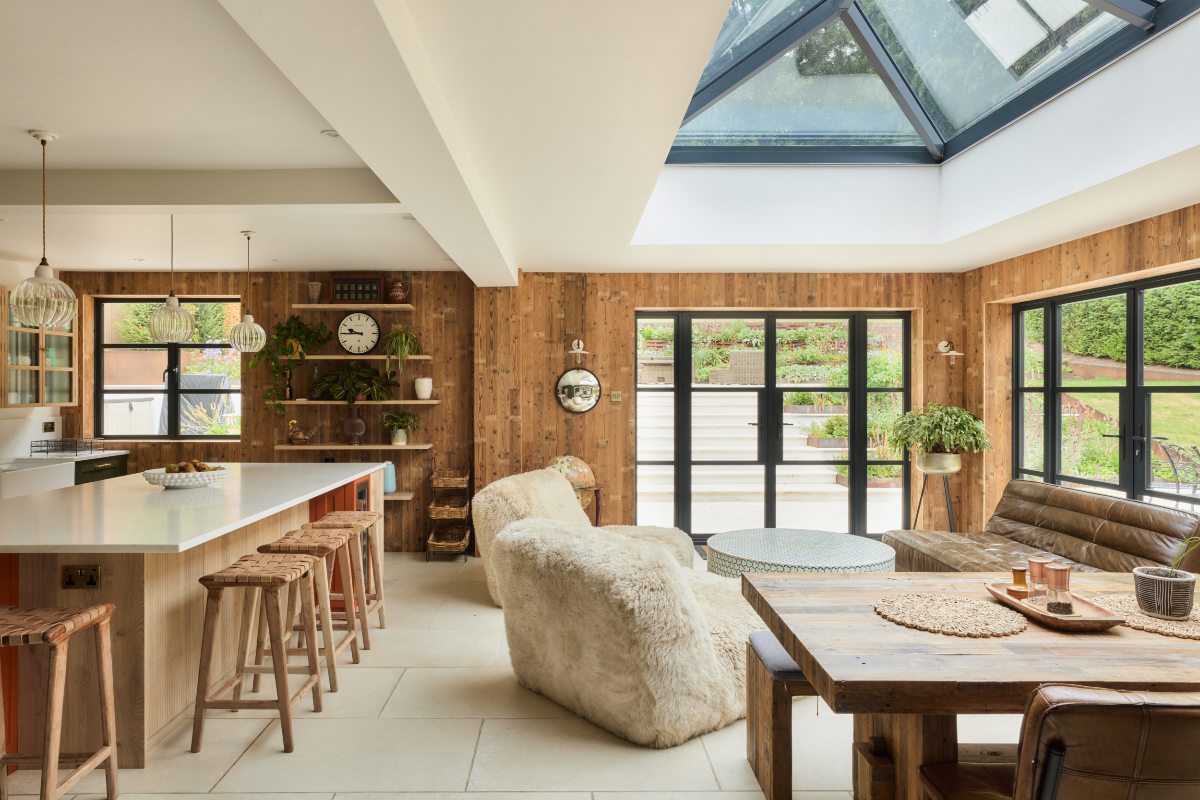 A cosy kitchen design drenched in wood with relaxed seating and dining areas.
