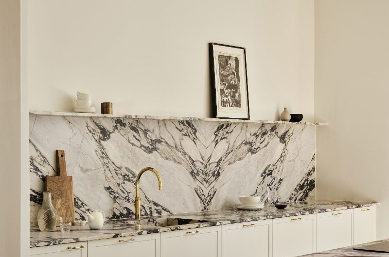 A Scandi kitchen with calacatta viola marble, a gold tap, and neutral wall and cabinet paint.