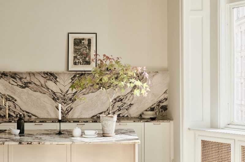 Closeup at the island with viola marble worktop and wood stools.