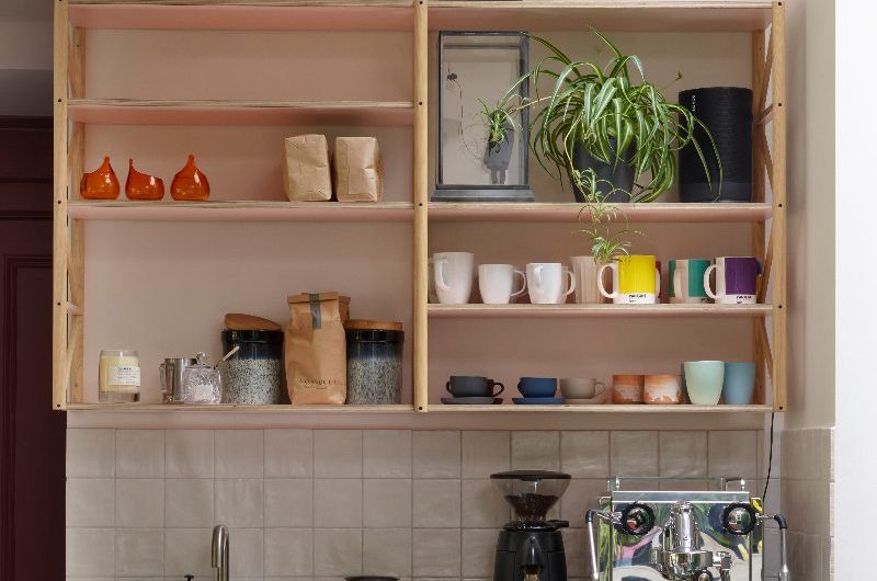 A kitchen corner with a coffee station, open shelving, and a small sink and tap.