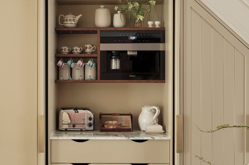 A bespoke breakfast cupboard under the stairs with bi-fold doors and neutral interiors.