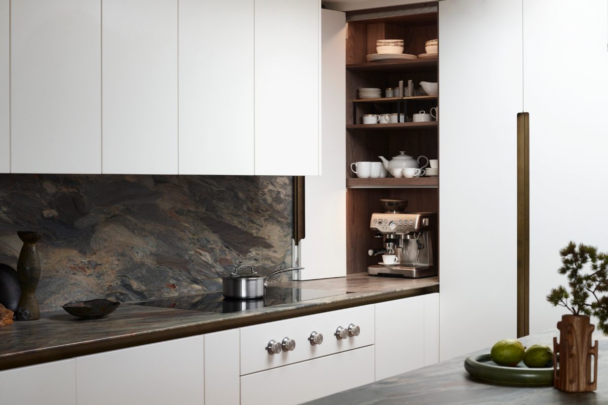 A white kitchen design with dark worktops and a compact dresser with oak interiors and bi-fold doors.