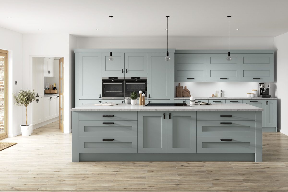 A light blue kitchen with matching units and island, with wood flooring and black hardware.