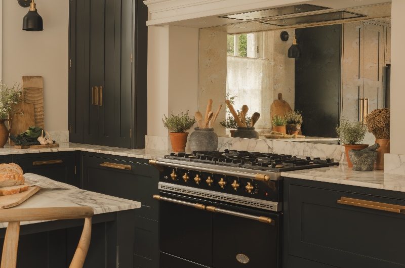 A range cooker area with a mirrored splashback, storage cabinets, and a concealed extractor.