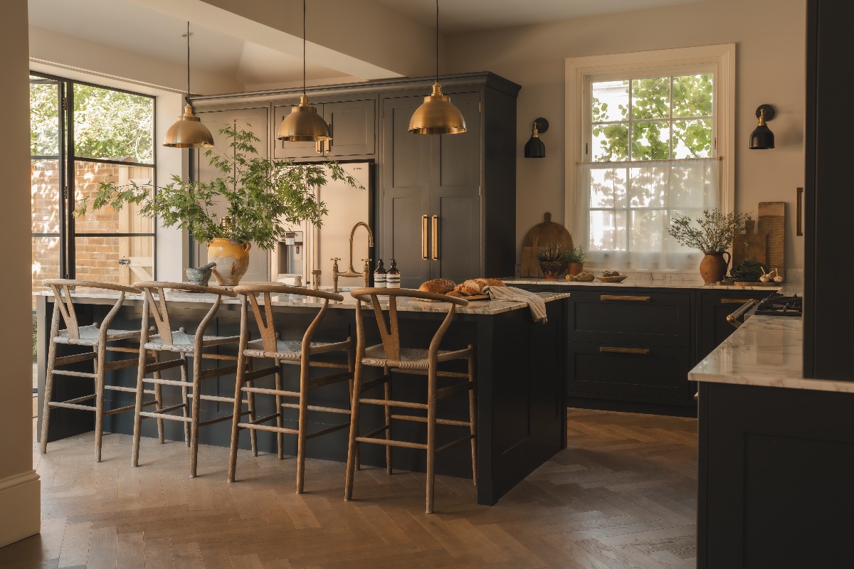 A bold kitchen design with black shaker cabinets, marble surfaces, wood flooring, and glazing.