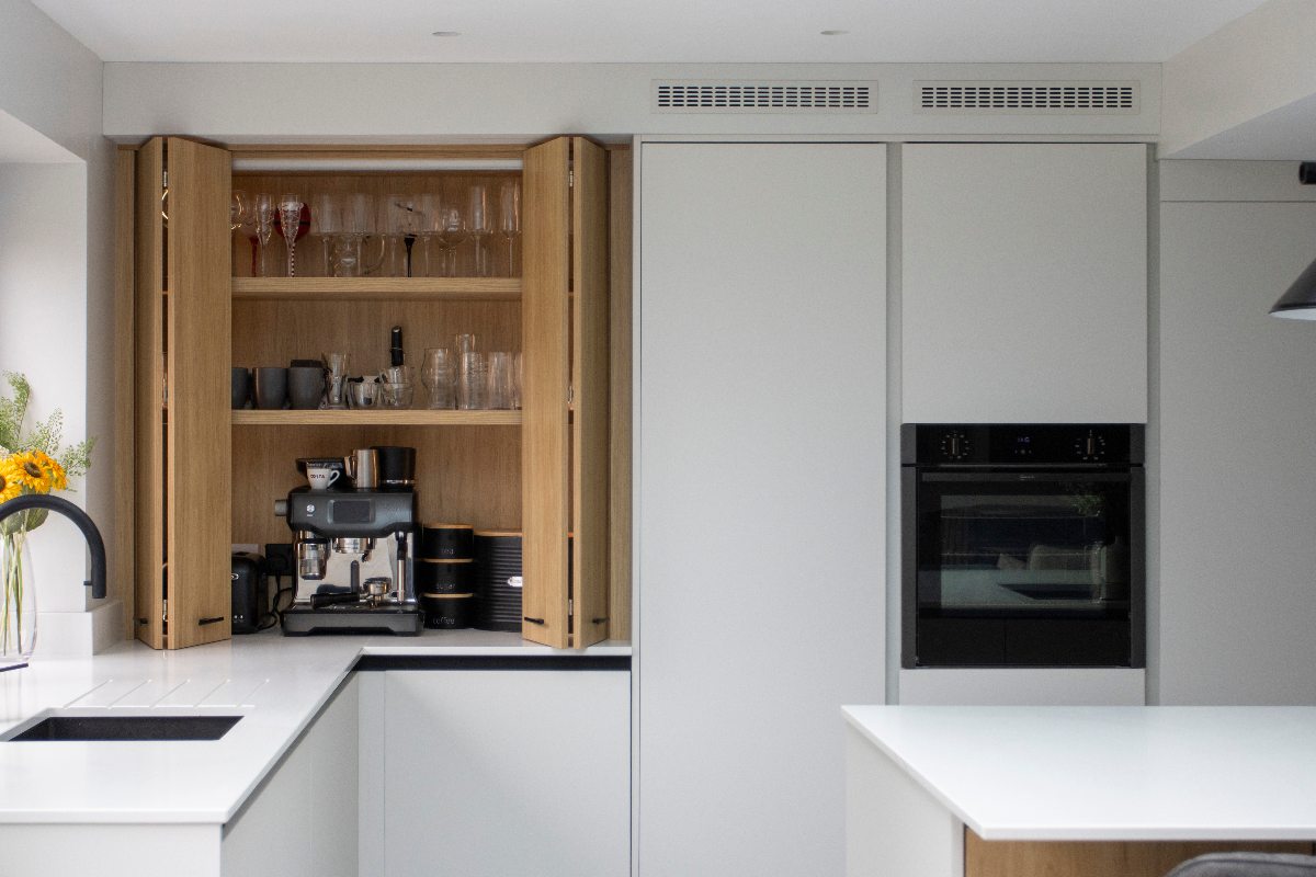A white kitchen with handleless units and an oak breakfast cupboard.