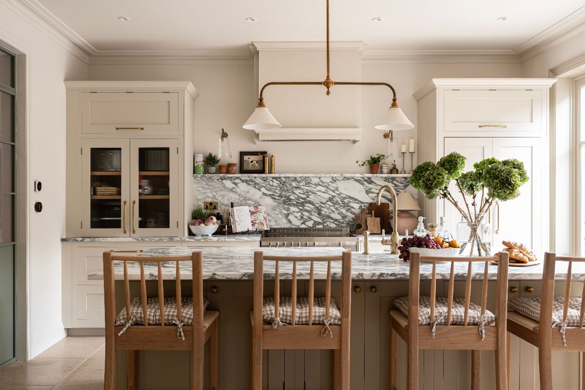 A neutral scheme with Shaker cabinets, a central island with seating, and statement marble surfaces.
