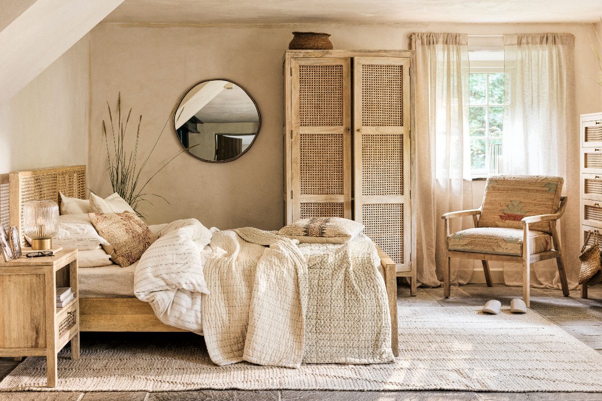 A rustic bedroom with rattan wardrobe, plaster walls and wood furniture.