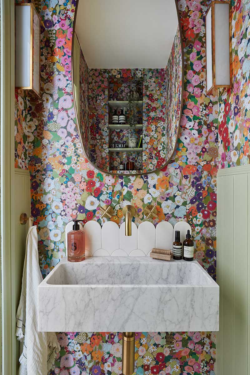 This cloakroom features a white basin with scalloped edges underneath a pill-shaped mirror