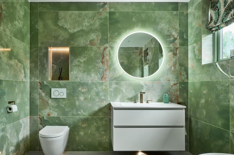 Vanity zone with wall-mounted handleless unit painted in white with an LED mirror and a toilet area with a niche above it.