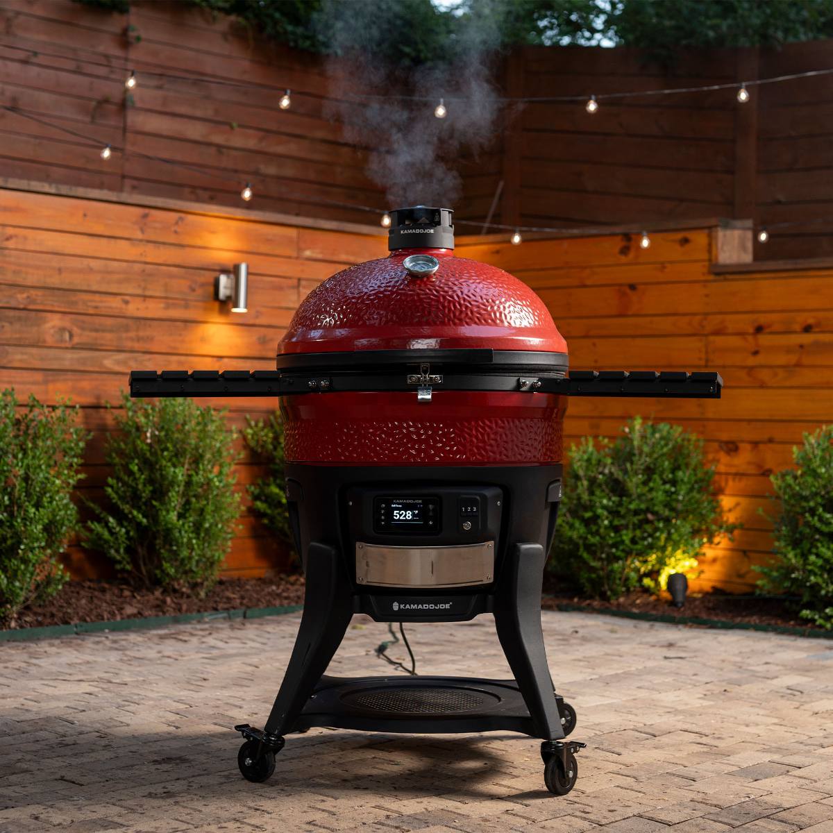 Komado Joe red cooking appliance in a garden.