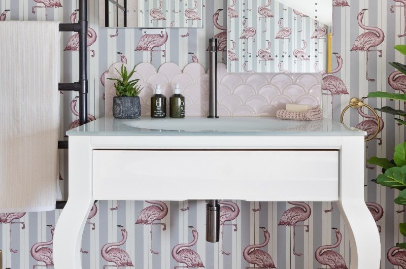 A playful kids bathroom with scalloped tiles, flamingo wallpaper and double mirrors above the vanity.