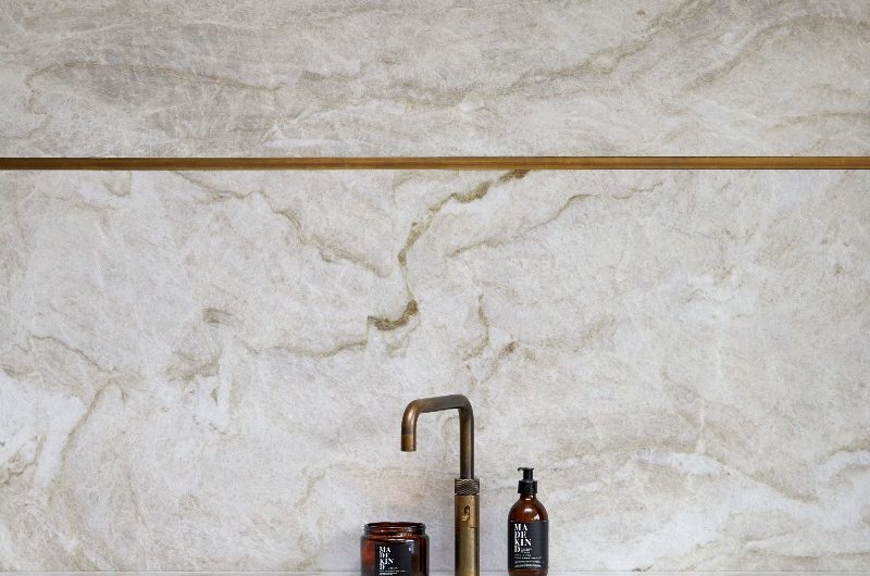 Closeup at the washing up area with statement surfaces, an inset sink and brass tap.