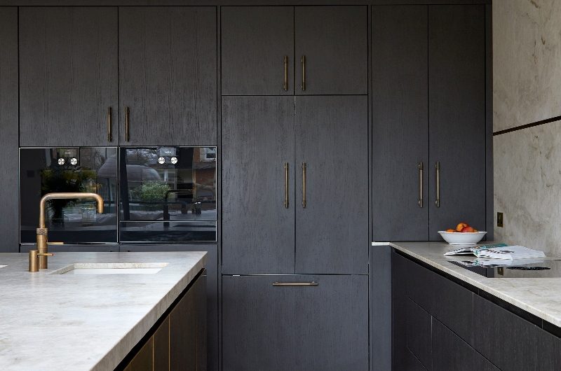 L-shaped kitchen layout mirrored by the island, with herringbone flooring and veiny worksurfaces.