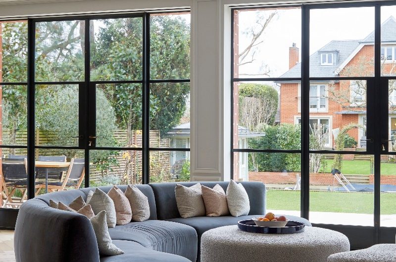 A seating zone with a plush sofa and steel-framed glazing.