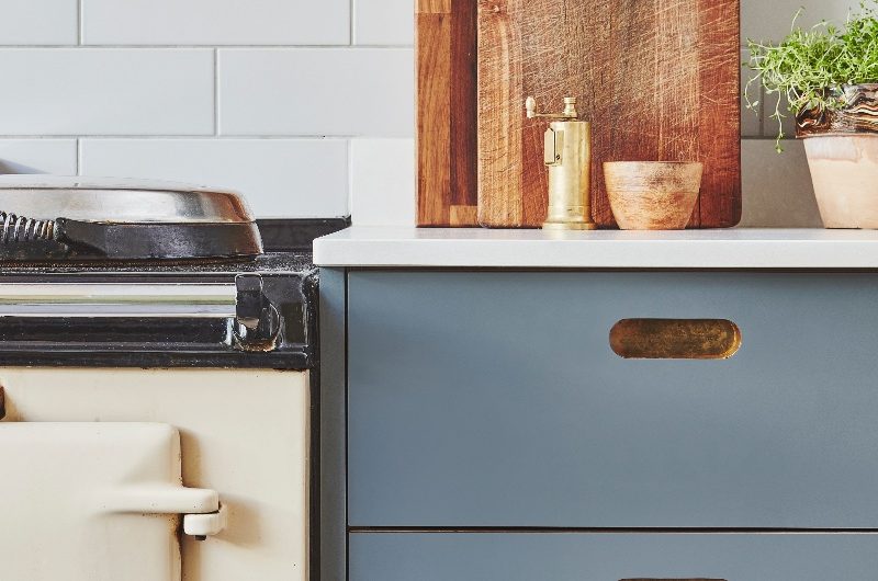 Blue kitchen design with cut-out handles, white tiles, and classic appliances.