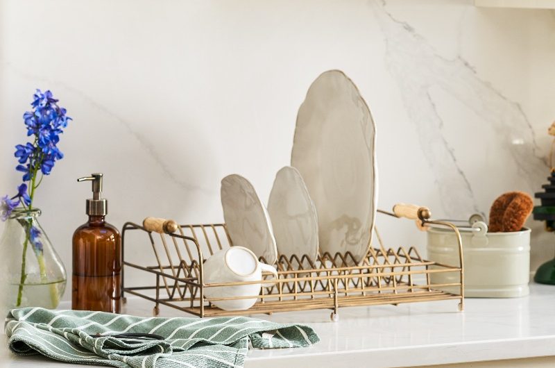 Classic neutral kitchen with Shaker cabinetry, gold handles, and a matching plate rack in gold.