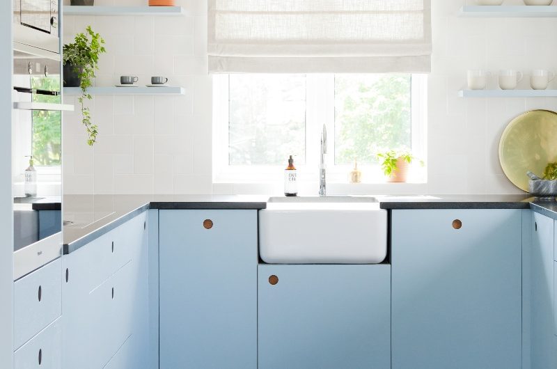U-shaped baby blue cabinetry with cut-out shapes, a butler sink and chrome tap.