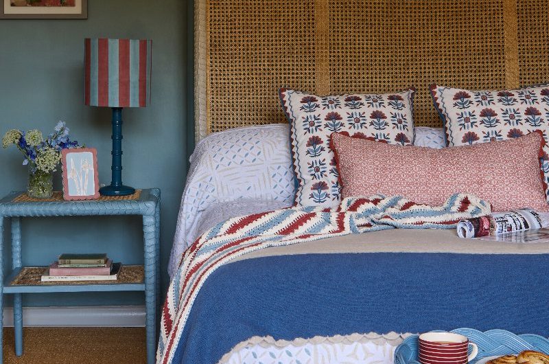 Modern folk bedroom with a mix of patterns, natural materials, and decor drenched in blues, greens and reds.