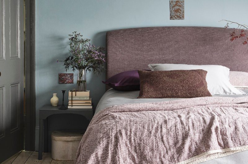 Bed bedroom with an upholstered bed, a compact side table and minimalist decor.
