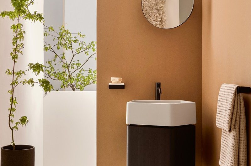 A terracotta coloured scheme with a wall-mounted storage unit, white basin, and small black tap.