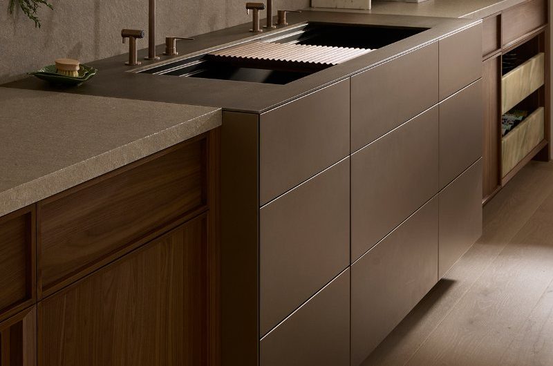 A washing up area with double bowls, matching taps, handleless furniture and open shelving.