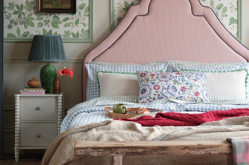 Panelled blocks of leafy wallpaper behind a thin striped headboard in an eclectic bedroom scheme.