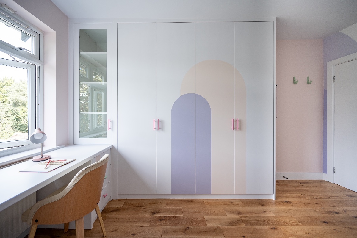 Dressing room with geometric shaped on the wardrobe, and a desk zone, all painted in light pastel hues.