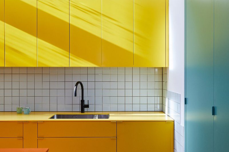 Modern design with furniture in primary shades, herringbone flooring, and square wall tiles.