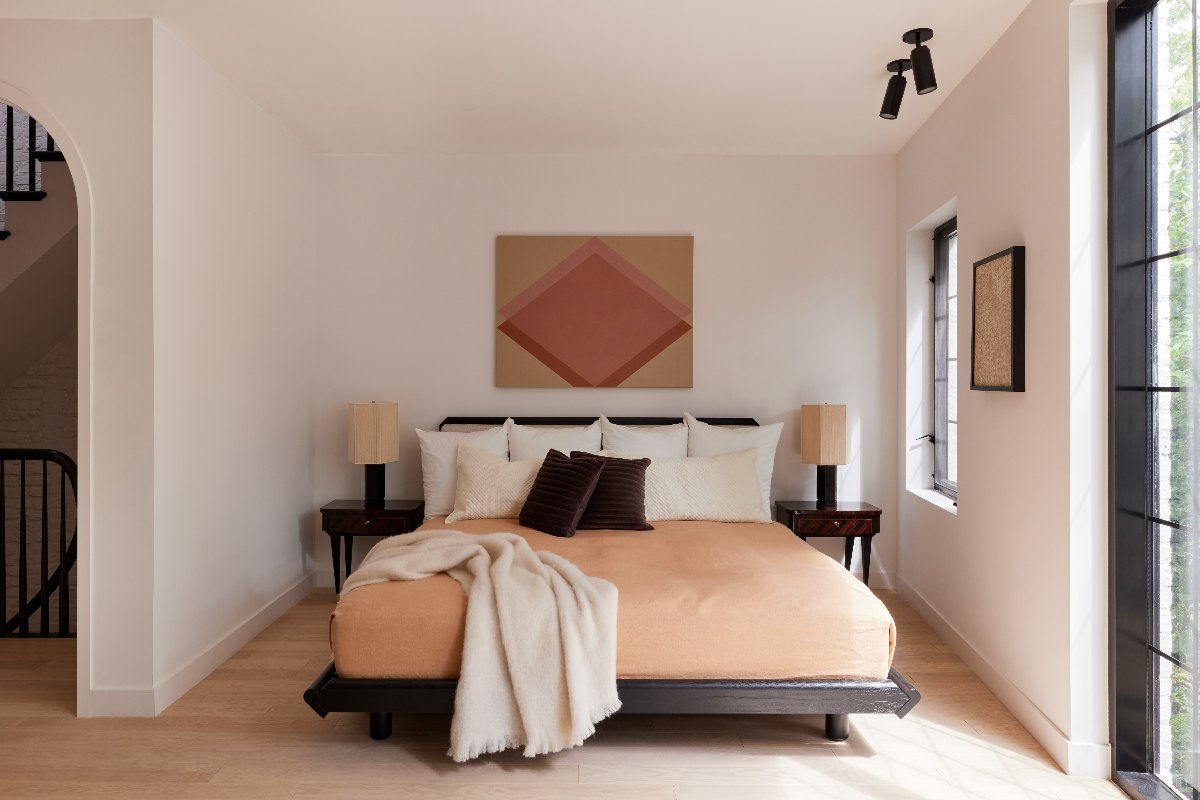 A bedroom with pastel hues and a wooden bed frame.