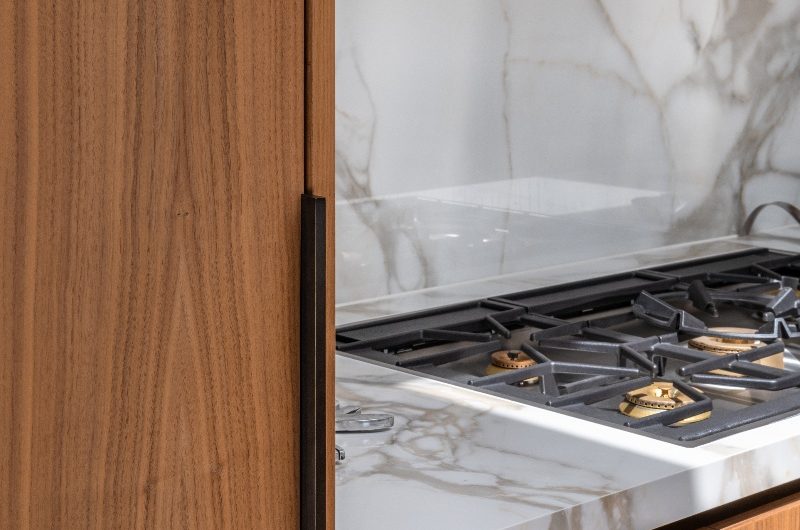 Wood cabinetry with veiny marble, gas hob and overhead extractor.