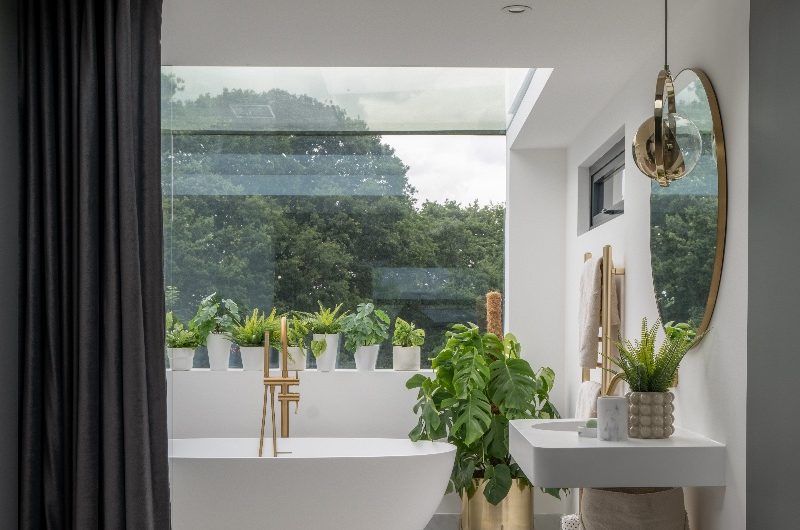 A luxurious hotel suite-inspired bathroom overlooking the garden, with a freestanding tub and plenty of storage space.