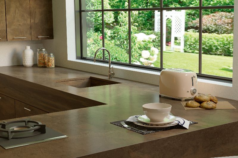 An L-shaped kitchen with neutral cabinetry and a sink made of the same worktop material.