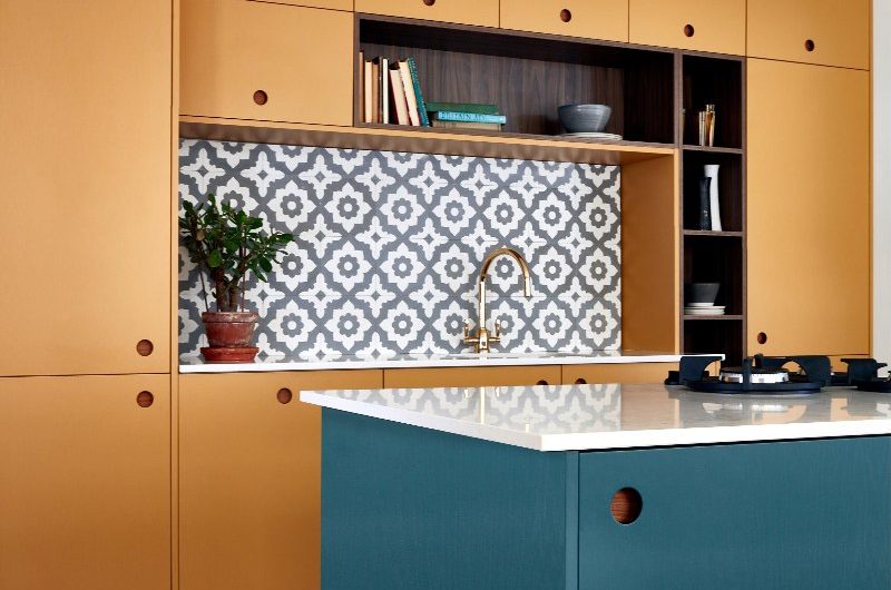 Mustard yellow kitchen with a mix of open and closed storage, patterned tiles, and a blue island.