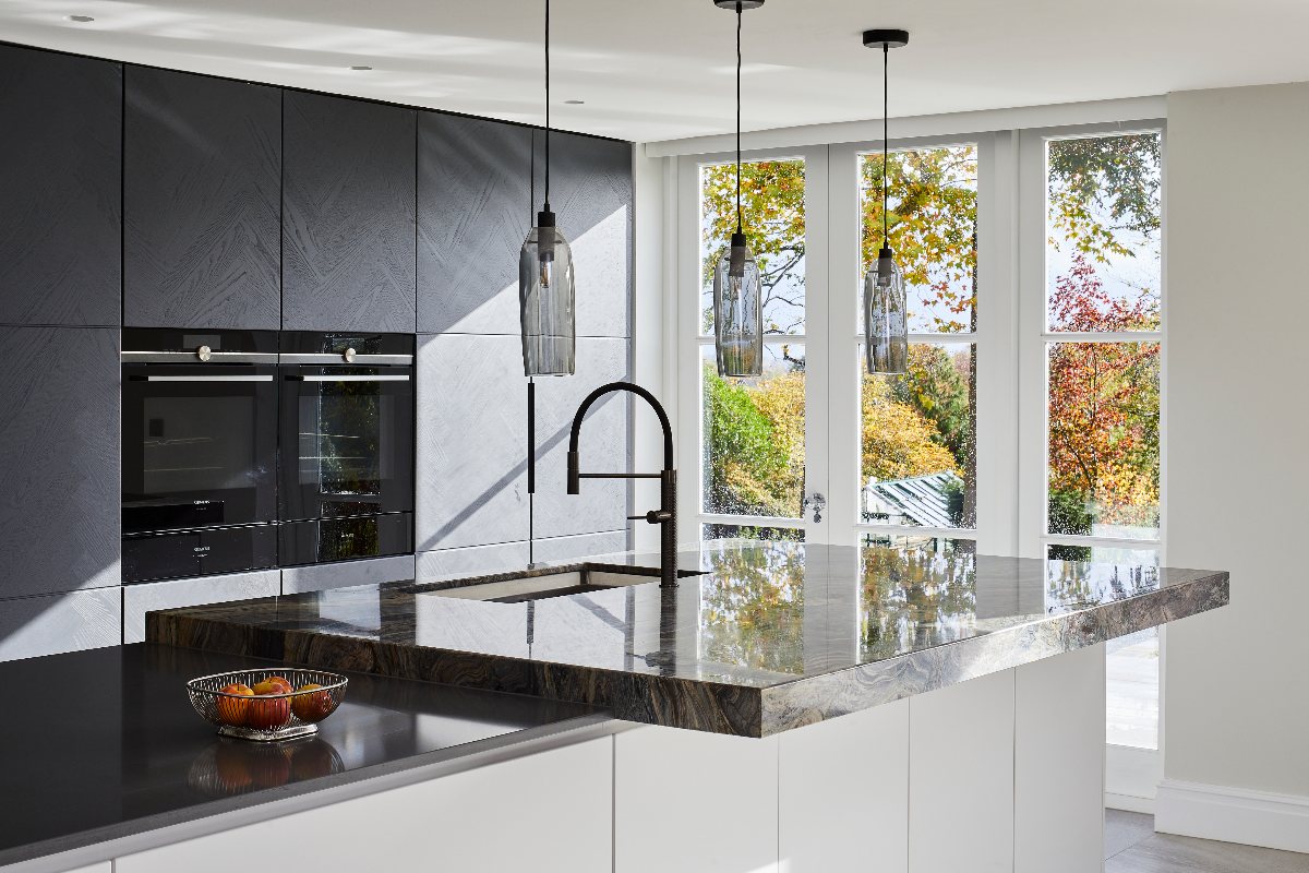 A modern design with a split-level island with an inset sink and dark worksurface.