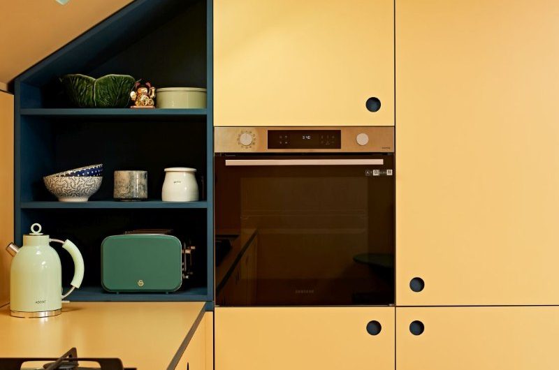 Colour-drenched loft with built-in appliances, a gas hob, and open shelving.