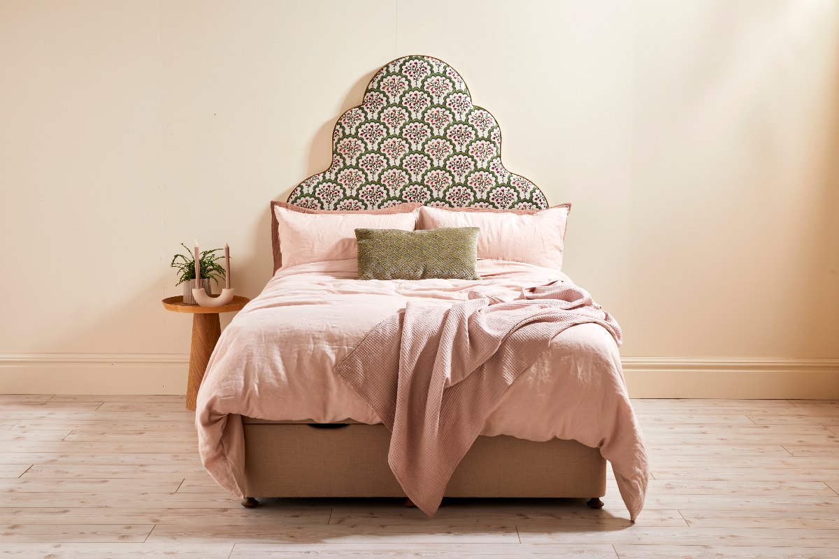 A simple scheme with neutral paint on the walls, a patterned headboard, and pink bedding.