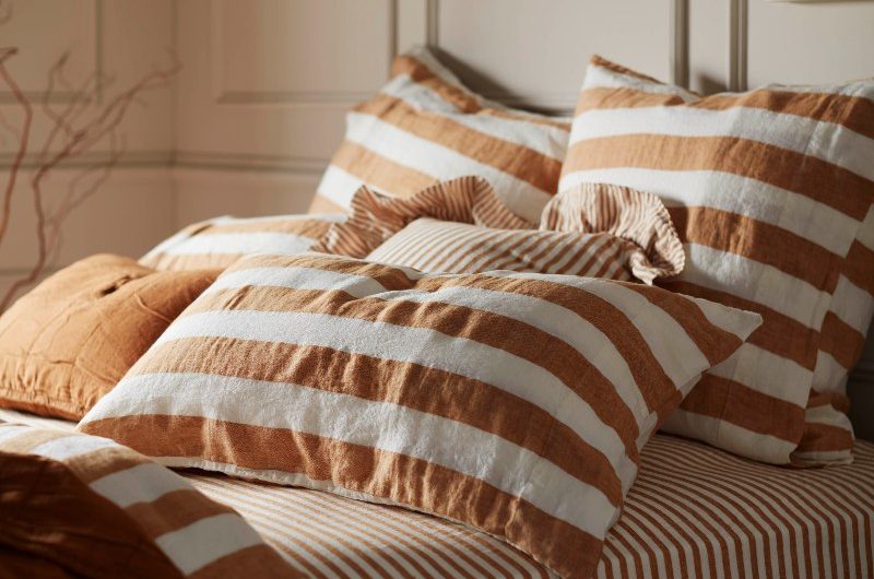 A bedroom with neutral wall panelling and striped bedding.