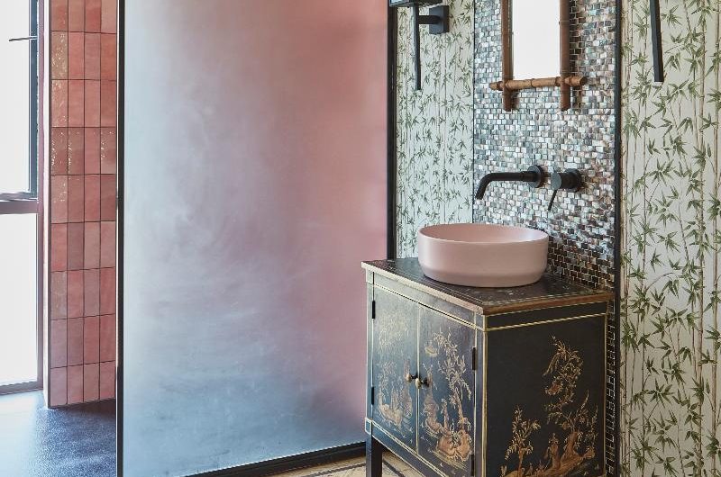A bathroom design with Chinoiserie elements, a frosted shower glass, and black accents.