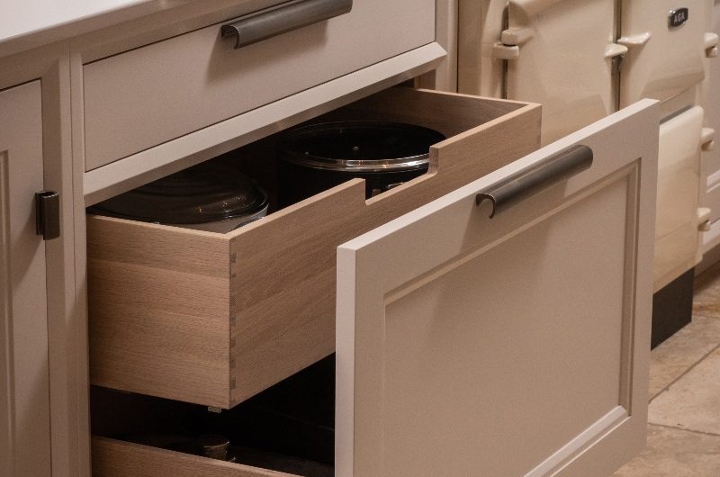 Open drawers with brass detailing near a range cooker.