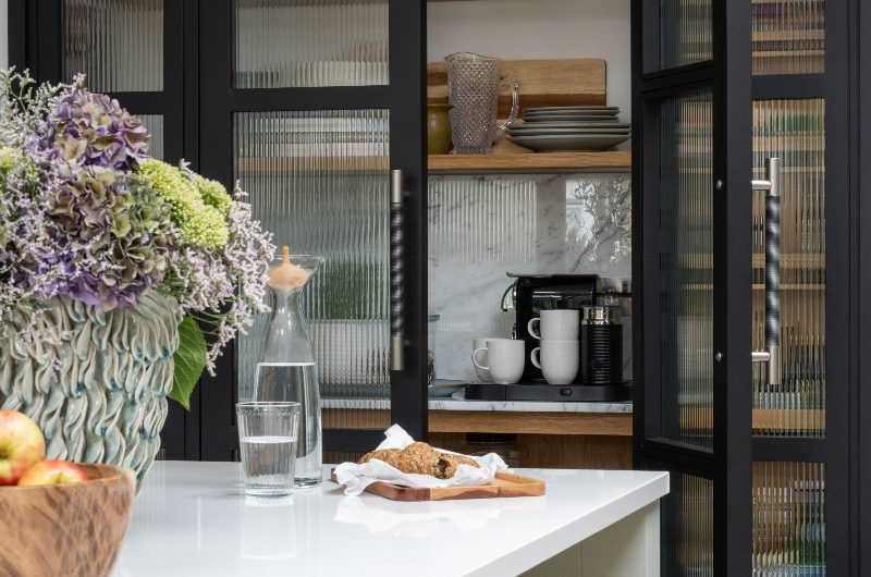 Modern scheme with walk-in pantry that features fluted doors and an island.
