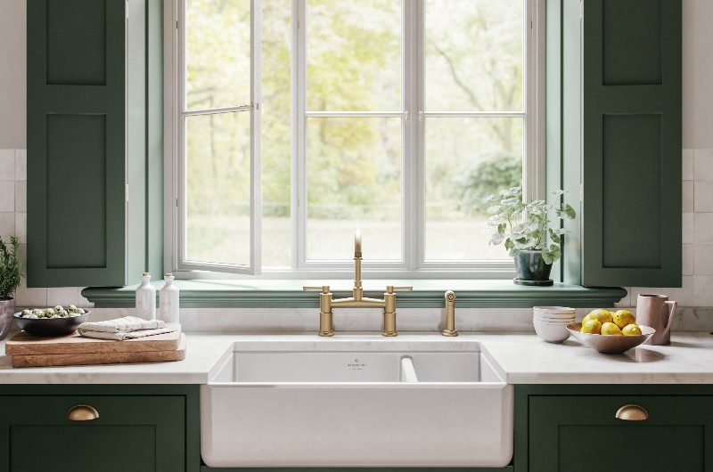 Kitchen design with classic cabinetry, a butler sink under a window, and brass tap.