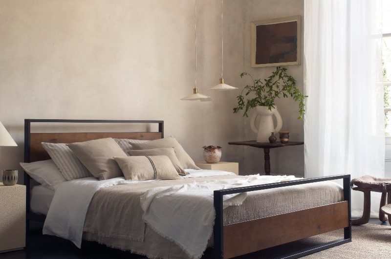 Neutral scheme with plaster on the walls, pendant lights, a metal bed frame, and wood flooring.