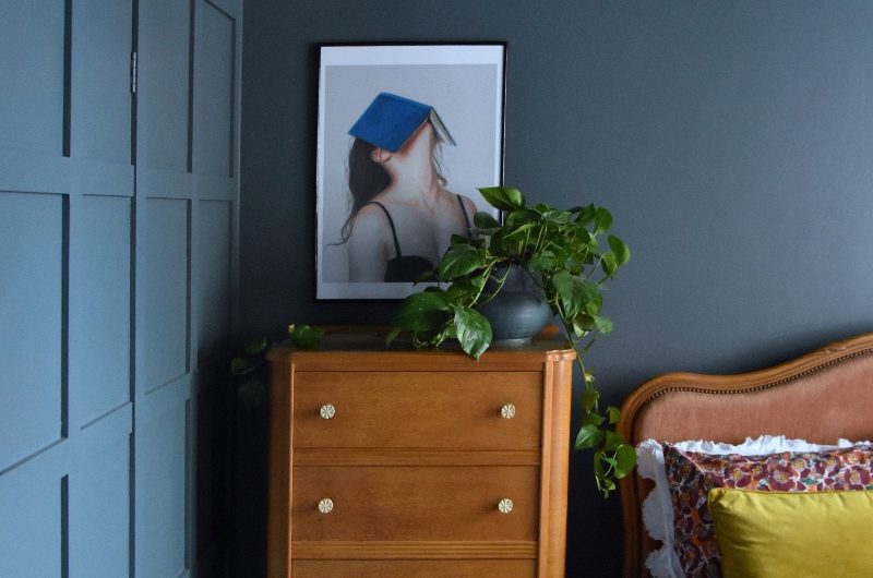 A colour drenched bedroom in blue with wood furniture and concealed storage.