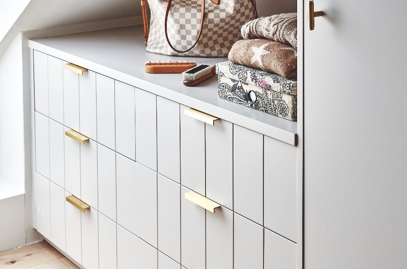 Fitted storage under eaves with gold handles.