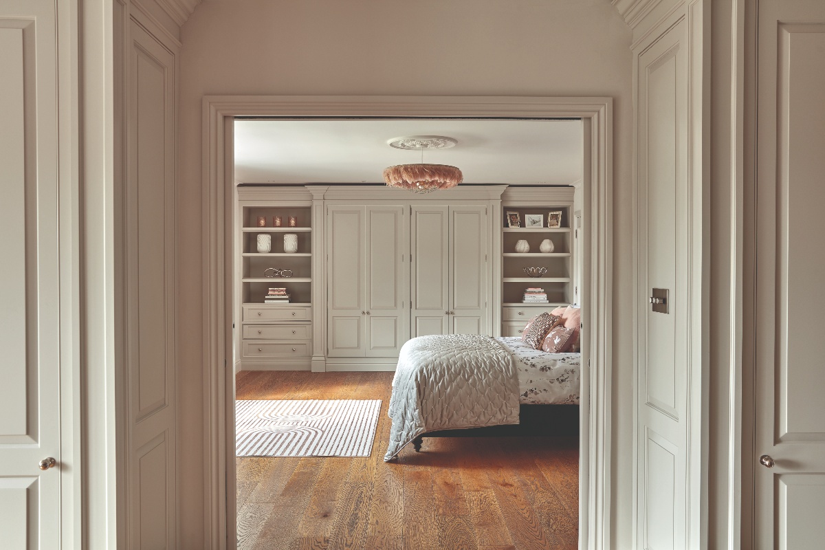 A luxurious sleep space with floor to ceiling wardrobes and open shelving for displaying decor.