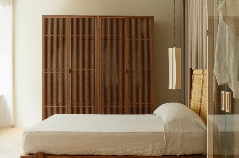 A calm bedroom design with wood storage, rattan bed, and neutral linen.