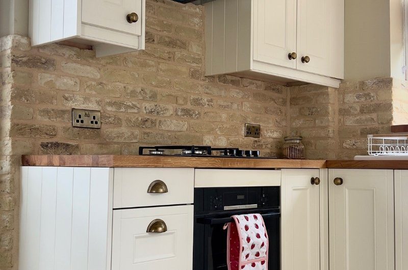Shaker cabinetry with exposed brick and brass finishes.
